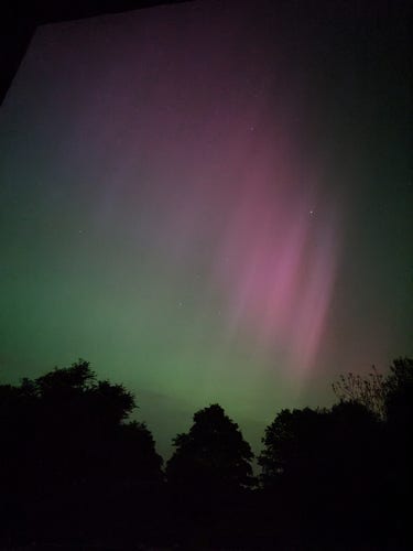 Picture of aurora in the sky with visible diagonal red streaks above and green below.