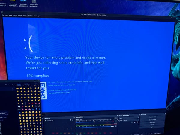 Computer screen displaying a blue error screen with a sad face emoticon, indicating the device has run into a problem and needs to restart. A stream setup interface and emoji picker can be seen overlaid on other parts of the screens.