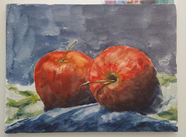 Two apples in front of a blue background painted with water color. The apples lie on a greenish kitchen blanket.
