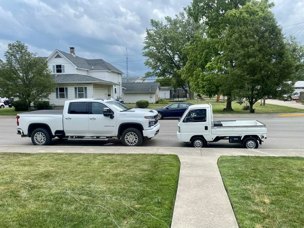 Two white pickup trucks facing each other, parked alongside a sidewalk and large lawn.

On the left, a huge GM truck with four doors and huge wheels and a hood that is at least a metre and a bit high.

On the right, a Japanese “keicar” truck which has the same size cargo bed, but the rest of the vehicle is much smaller. The front is nearly vertical so anyone larger than a toddler is visible to the driver at all times, and the wheels are regular sedan-size.  This allows it to fit in smaller spaces, to see pedestrian children easily, and even to load and unload the bed without as much reaching and strain.