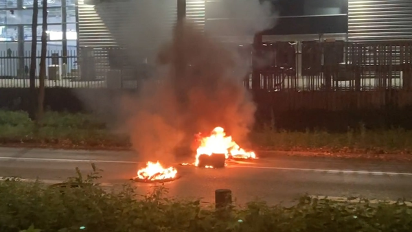 Bild zeigt eine brennende Barrikade in der Mitte einer Straße