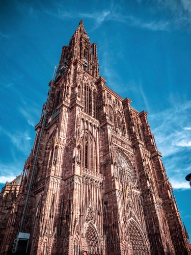 The Strasbourg cathedral photographed from the bottom left of the entrance reaches into the sky, with all the delicate ornaments visible in its earthy colour