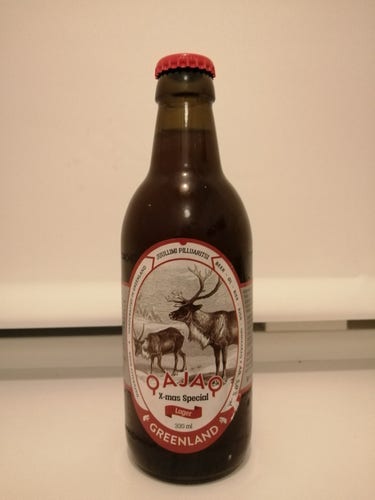 Une bouteille en verre contenant une bière spéciale Noël brassée au Groenland. Marque Qajaq. L'étiquette montre deux rennes.