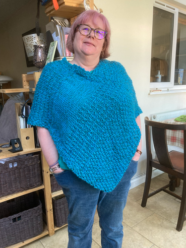 Woman in a hand knitted blue poncho 