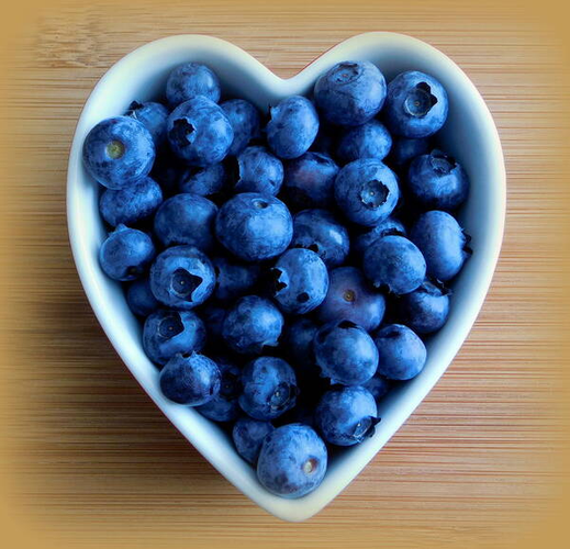 A heart-shaped dish holds blueberries.