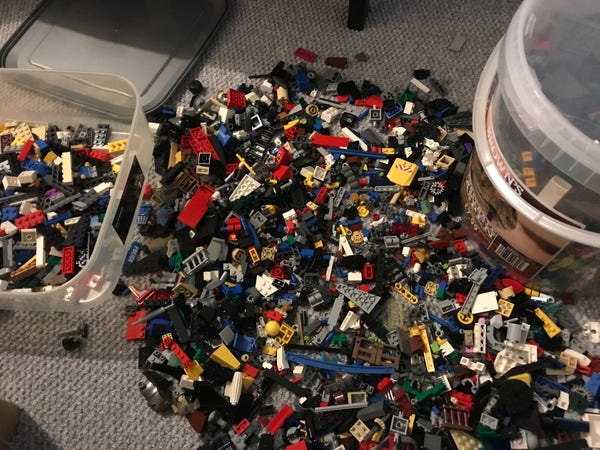 Huge pile of Lego in middle of carpet, plus tubs either side of that, also full of Lego 