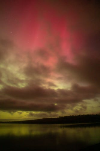 Pink aurora with clouds over water