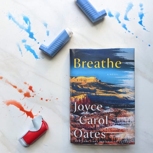 The book, Breathe, by Joyce Carol Oates. Two blue inhalers and one red inhaler a lying around the book. Water, matching the inhaler color is splattered.