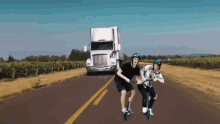 image of two people riding e scooters on a road next to a semi truck