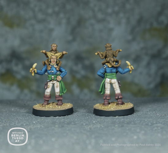 wargame model. female pirate with a small monkey on her shoulders, pulling her hair into bunches. She wears a blue top, greey sash and off-white trousers. She holds a bananna in one hand.