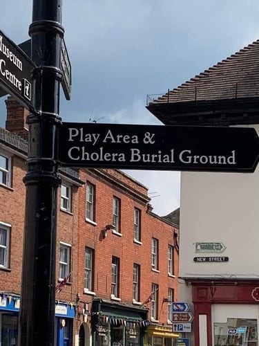 Beschilderung in Großbritannien.
"Play Area & Cholera Burial Ground"