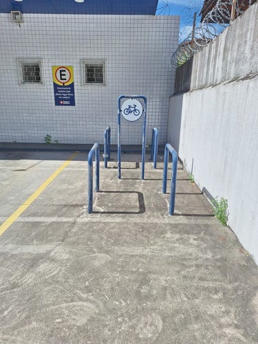 Fotografia de uma vaga de estacionamento na qual foram colocados quatro paraciclos, podendo comportar quatro a oito bicicletas