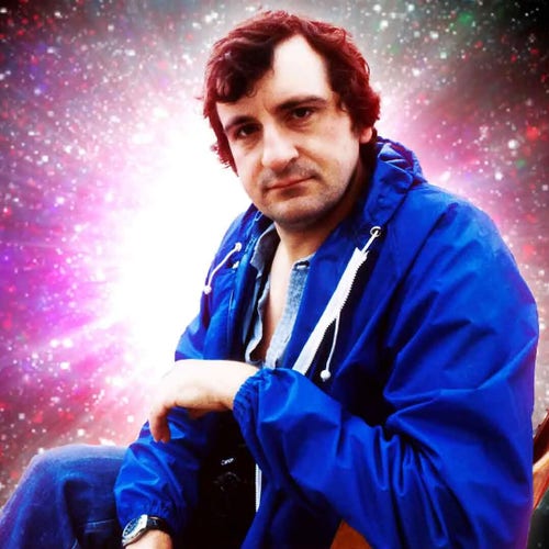 Author Douglas Adams in a blue anorak, looking directly into the camera with a serious expression. Behind him an image of an exploding galaxy has been added.