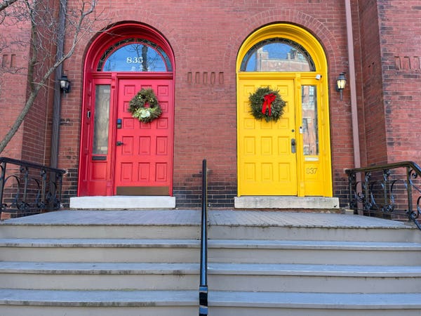 A brick house with two doors - one is red and the other is yellow.