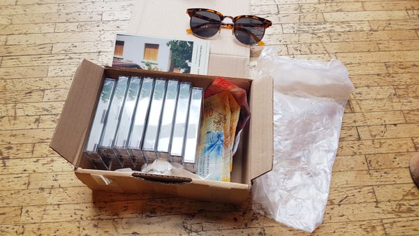 Un carton de cassettes, des billets suisses, cartes postales, lunettes, plastique d'emballage