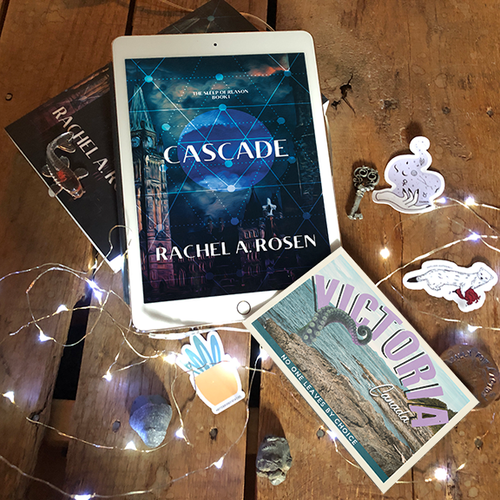 Cascade on my ipad surrounded by glass koi, stickers of a hand doing magic, an otter, and a cactus, various fossils, a postcard from Victoria with a tentacle on it, and fairy lights.