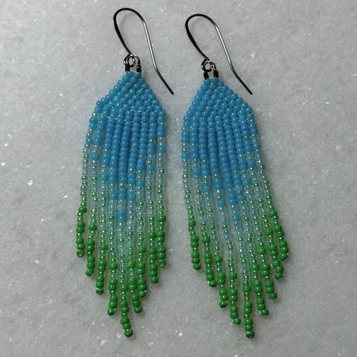 Blue to green ombre Native beaded fringe earrings on a marble background