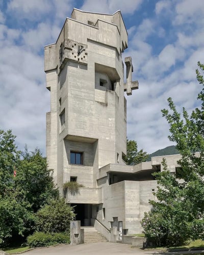 Photo of a Brutalist-style concrete church with a tall, narrow, multi-faceted tower