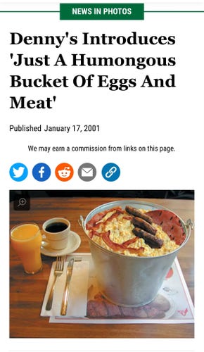 An oversized breakfast meal in a large bucket, with scrambled eggs, bacon, and sausage, accompanied by a glass of orange juice and a cup of coffee on a table. The headline says Denny’s introduces just a humongous bucket of eggs and meat