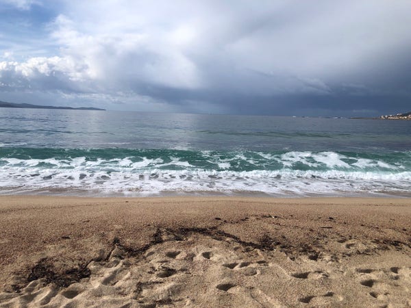 Plage de sable en Méditerranée, ciel couvert, eau verte.