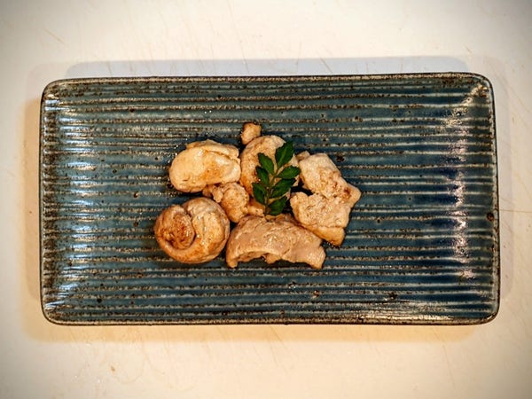 A small rectangular blue plate with small cream and browned blobs and a kinome sprig