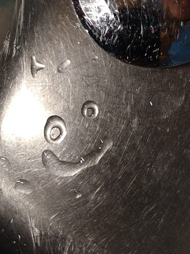 Close-up of the bottom of a kitchen sink. Two rings of water have formed above a curved line of water - they look like a happy face.