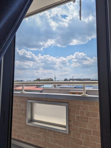 A small apartment balcony with blue partly cloudy skies in the distance 