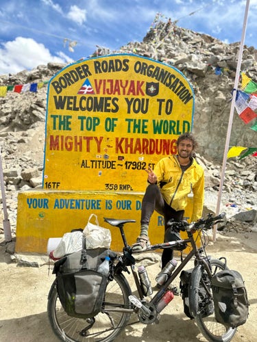 Je pose avec mon vélo devant le panneau « welcome to the top of the world mighty Khardung »