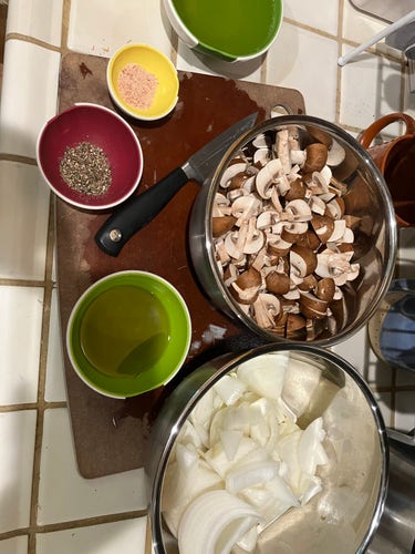 Mise en place: sliced mushroom, chunked onion in metal prep bowls; portions of evoo, white wine, salt, pepper in rubbery prep bowls. 