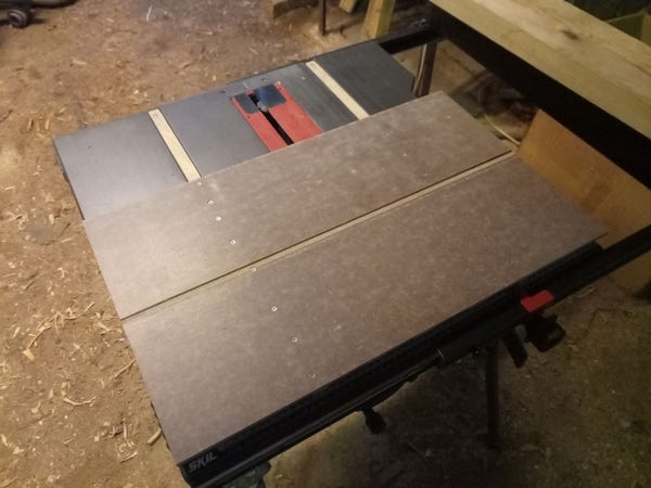 Crosscut sled bottom, consisting of two glued together floorboard offcuts (smooth side down) with two wooden strips installed with countersunk screws. The whole thing rests on a table saw.