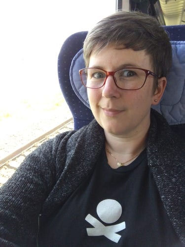 Selfie taken in train, wearing a shirt with the pirateship.com logo on it (an extremely simplified or minimalist skull and crossbones)