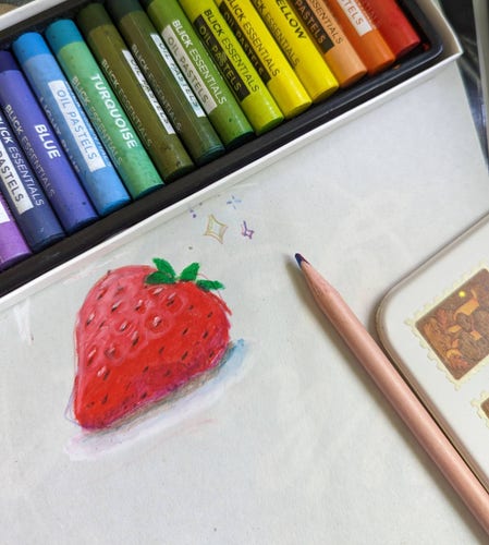 Top down photo of a paper with a colorful drawing of a strawberry on. Set on the edges of the paper is a set of oil pastels in colors of the rainbow, and a colored pencil.