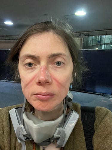 me outside of LAX at night looking like traumatized shit with deep grooves in my face from wearing a probably too tight respirator 