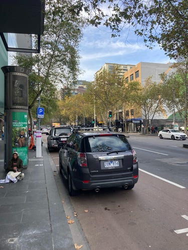 Cars parked along Lonsdale Street in parking bays that form part of the bus lane. Photo taken from a bus stop.