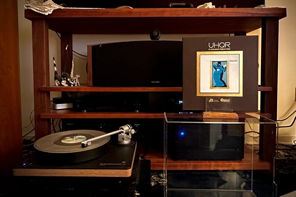 Medium shot of some of my audio setup: 

Turntable: ClearAudio Performance DC Wood, w/ Carbon tonearm and Hana SL cartridge. 

AQVOX MC phono stage

Hegel 190 acting as a preamp. 

PSAudio BHK250 hybrid amp 

Bowers and Wilkins 803D L&R channels

Atop the removed custom TT cover is my ‘now playing’ jacket holder, which shows the outer box of the UHQR Gaucho album. Standard brown, with gold lettering. The original album art is inset. 