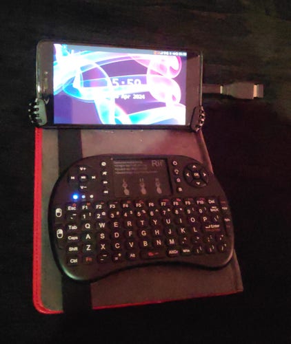 A mobile phone connected with a mini keyboard via Bluetooth.  The phone screen shows the sxmo mobile environment.