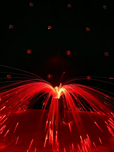 A fiber optic lamp that is in the red phase against the backdrop of my headboard.