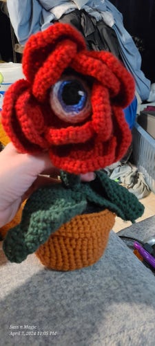 A red flower with a blue eye in the center, all crochet.