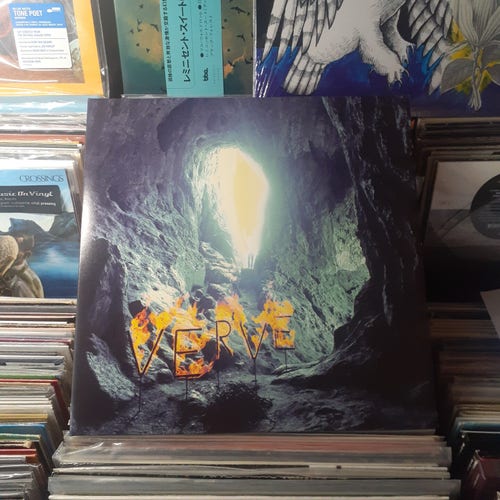 Album cover features a blue tinted photo of the interior of a cave, with the letters VERVE burning in the foreground. In the background, a mystical, barely visible figure stands at the entrance of the cave, arms outstretched in the blinding light.