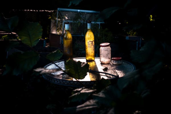Bottles on a table, lit by a ray of light. Everything around in darkness.