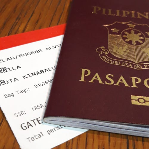 Photo of a boarding pass for a flight going to Kota Kinabalu, Malaysia that is partially hidden by the cover of a Philippine passport