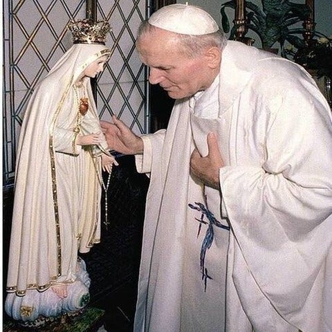 The pope bowing before a small statue of Mary. It looks like their sharing a quiet conversation.