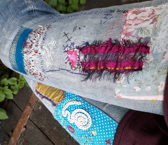 A pair of jeans, heavily mended with colourful patches.