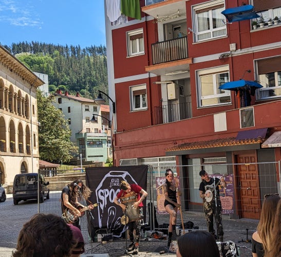 A band playing music in the sun on a street in a small Spanish town.