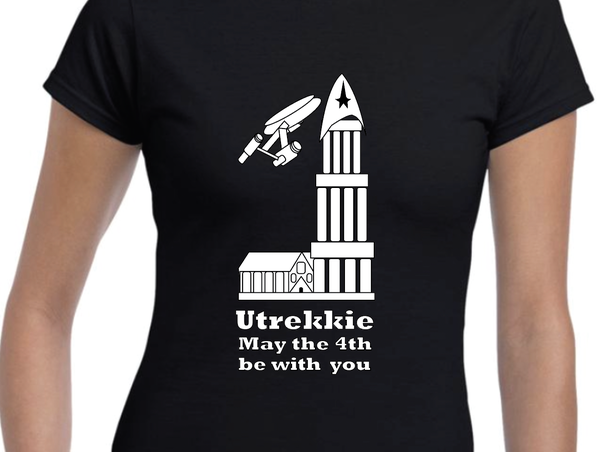 Person wearing a black t-shirt with the words Utrekkie May the 4th be with you. There is a graphic of a cathedral and spaceship above the words.