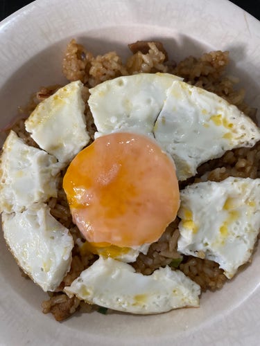 Sunny side up cut to resemble a flower with the whites as flower petals and the yolk in the center, laid out over fried rice