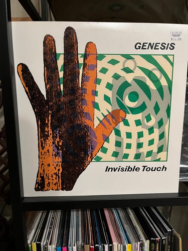 Album cover with a large orange hand and a field of interlocking green and tan circles 