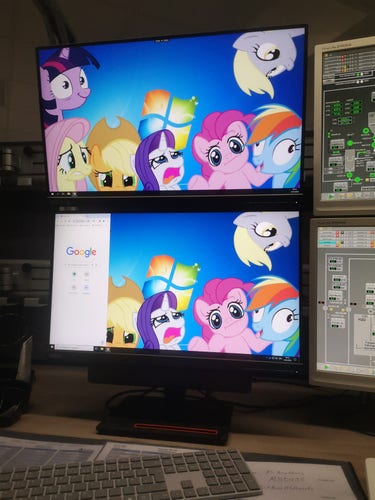 A two-monitor desktop setup with the default Windows7-Background... but with My Little Pony ponies inserted, who make funny faces. 