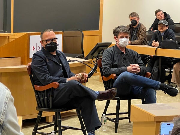 Corey Doctorow and Randall Monroe, seated in fancy wood chairs at the front of a Harvard classroom. 