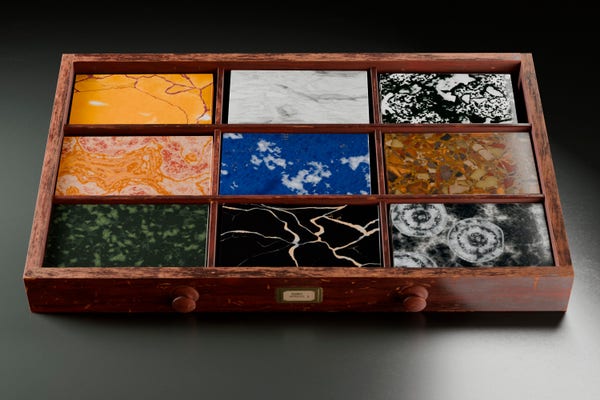 An old, worn-out drawer containing nine samples of ancient marble.